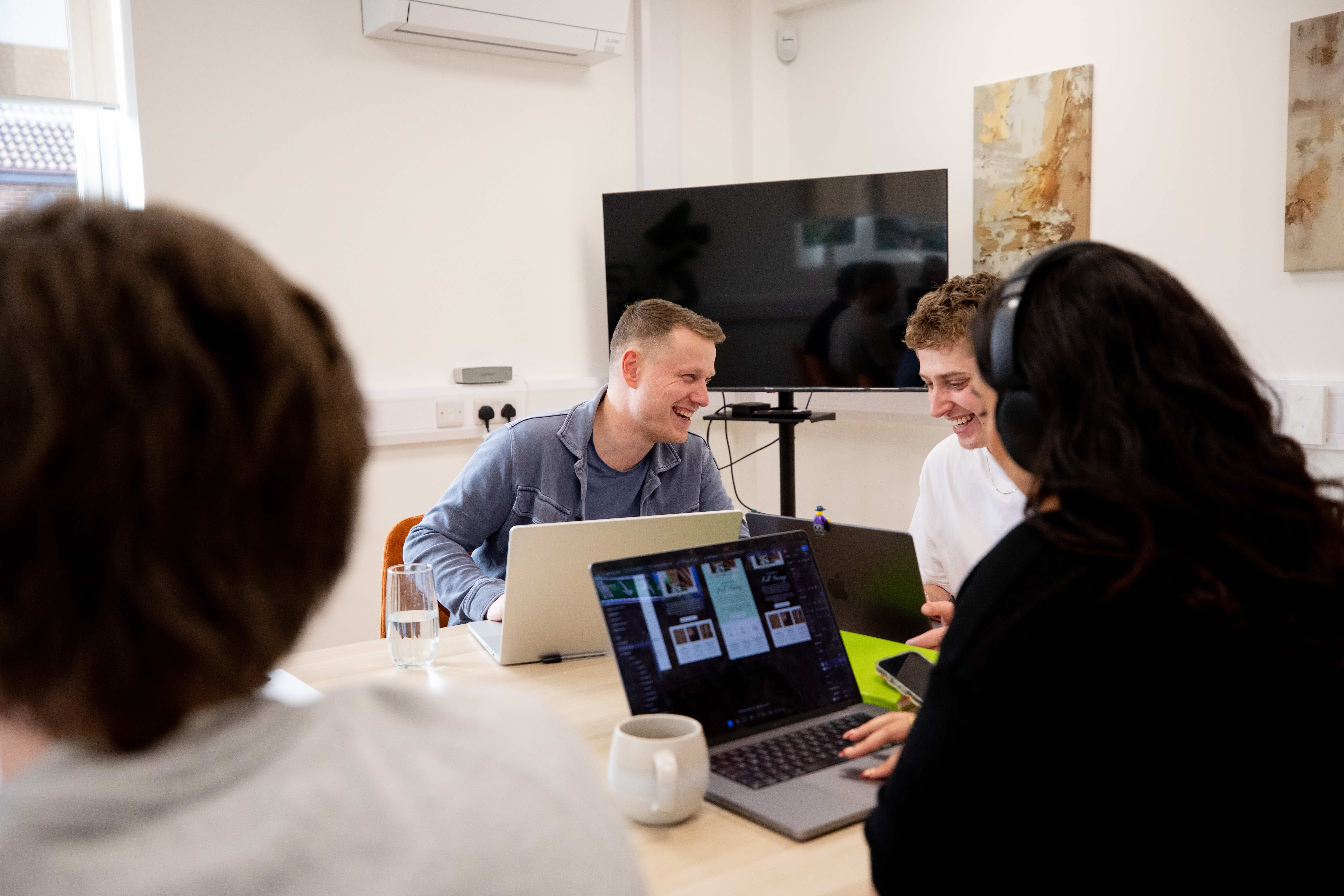 Photo of smiling team members around laptops